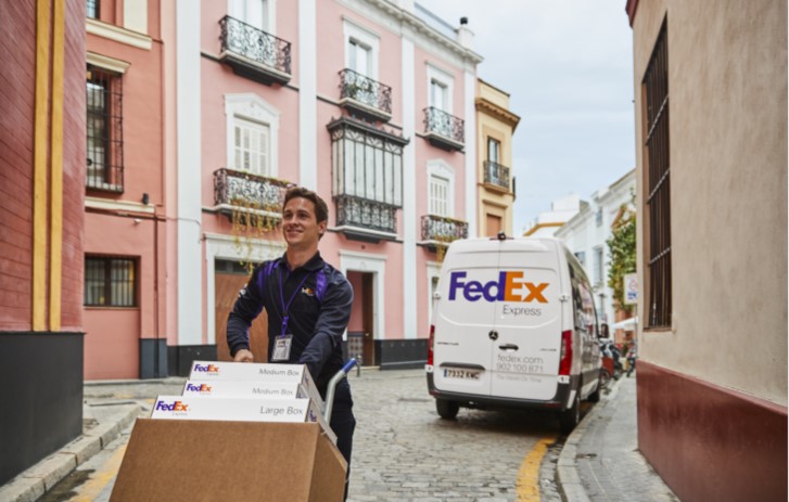 Pekerja FedEx sedang membawa paket dengan gerobak sorong